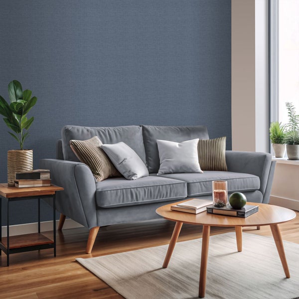 Wohnzimmer mit grauer Couch, Holztischen und Zimmerpflanzen vor einer blauen Wand