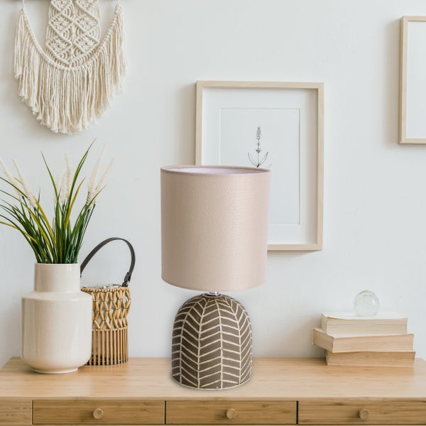 Dekorative Tischlampe mit gemustertem Fuß auf einem Holztisch