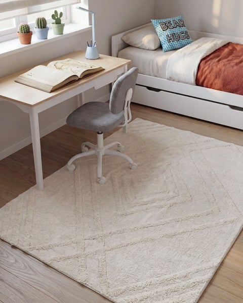 Helles Kinderzimmer mit Schreibtisch, Schreibtischstuhl, Einzelbett und einem strukturierte Teppich mit geometrischem Muster auf Holzboden.