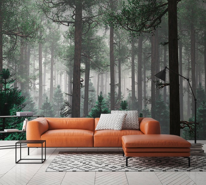 Modernes Wohnzimmer mit Fototapete im Wald-Design, Ledersofa und Hocker vor nebeligem Nadelwald auf hellem Parkettboden.