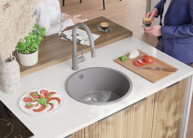 Küchenszene mit Spüle, Armatur, Schneidebrett mit Zutaten, Teller mit Caprese und zwei Personen