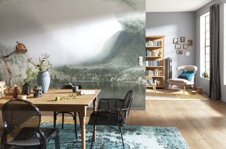 Esszimmer mit Holztisch, Stühlen und Fototapete mit Bergmotiv.