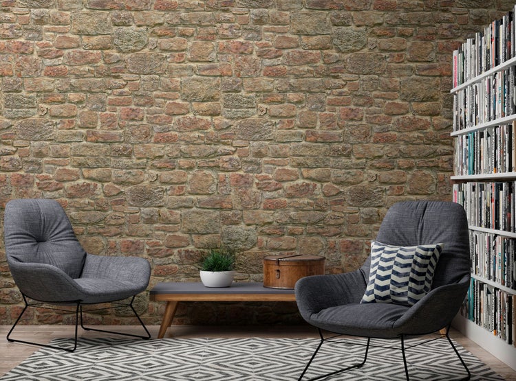 Gemütliches Wohnzimmer mit Steintapete, Sesseln, Couchtisch, Teppich und Bücherregal
