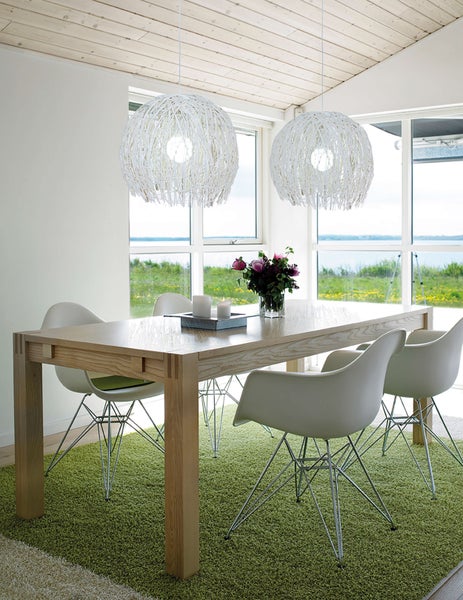 Heller Essbereich mit Holztisch, weißen Stühlen und zwei kugelförmigen Pendelleuchten.