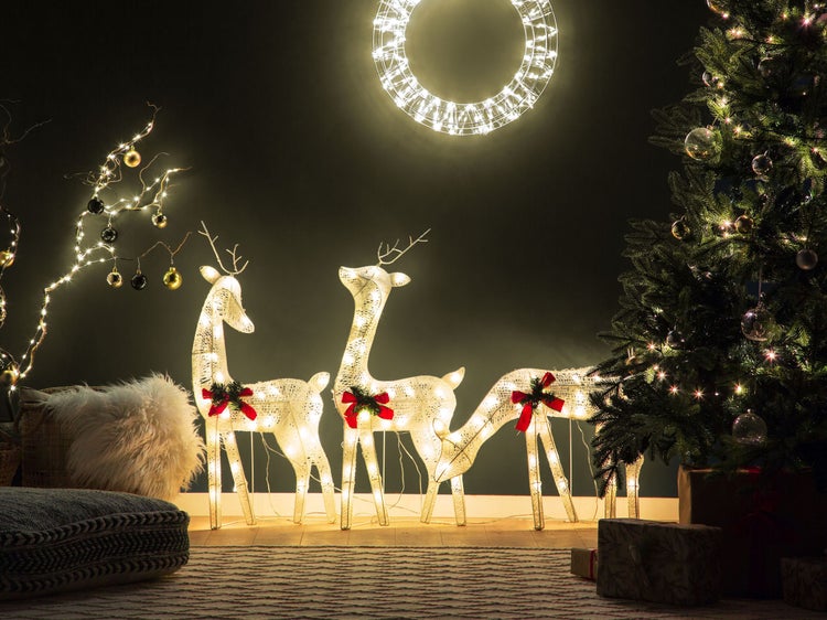 Festliche Dekoration mit beleuchteten Rentieren, Weihnachtsbaum und leuchtendem Kranz für eine stimmungsvolle Atmosphäre.