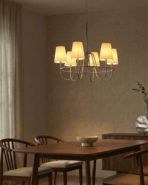 Heller Essbereich mit klassischem Kronleuchter mit Stoffschirmen über einem Holztisch, gepolsterten Holzstühlen und gemusterter Tapete.