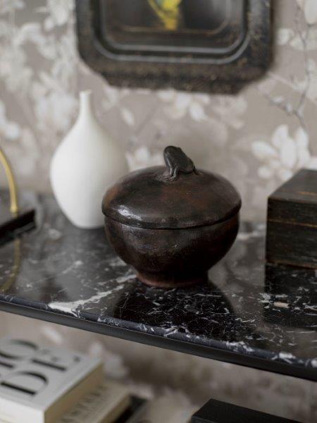 Wohnzimmer mit Sofa, Tisch, Bank und floral gemusterter Tapete