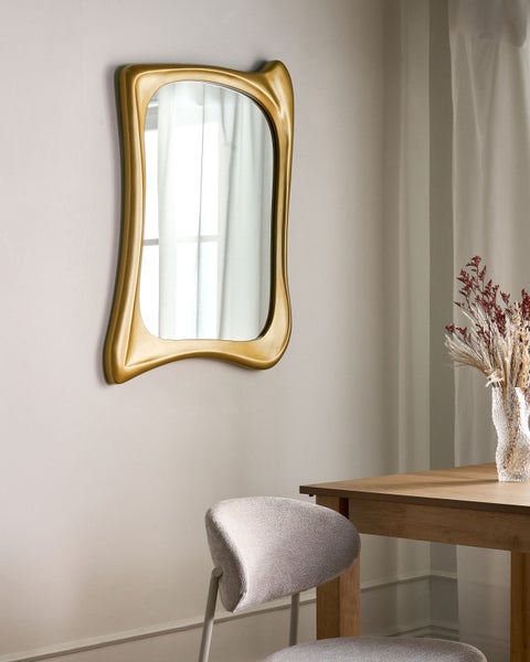 Dekorativer Wandspiegel mit goldenem Rahmen über Esstisch und Stuhl
