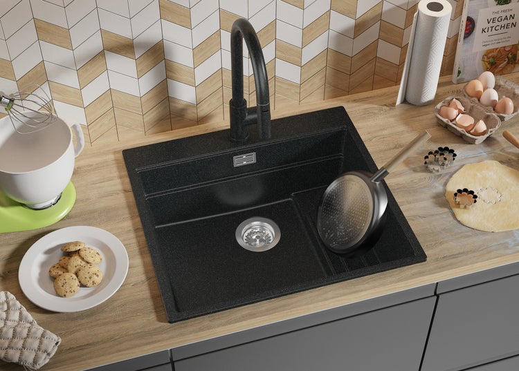 Schwarze Küchenspüle mit Armatur auf einer Küchentheke mit Utensilien