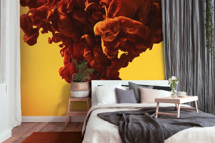 Vlies-Fototapete mit abstraktem Motiv aus orange-roten Rauchwolken in einem Schlafzimmer mit weißem Bett und grauen Vorhängen.