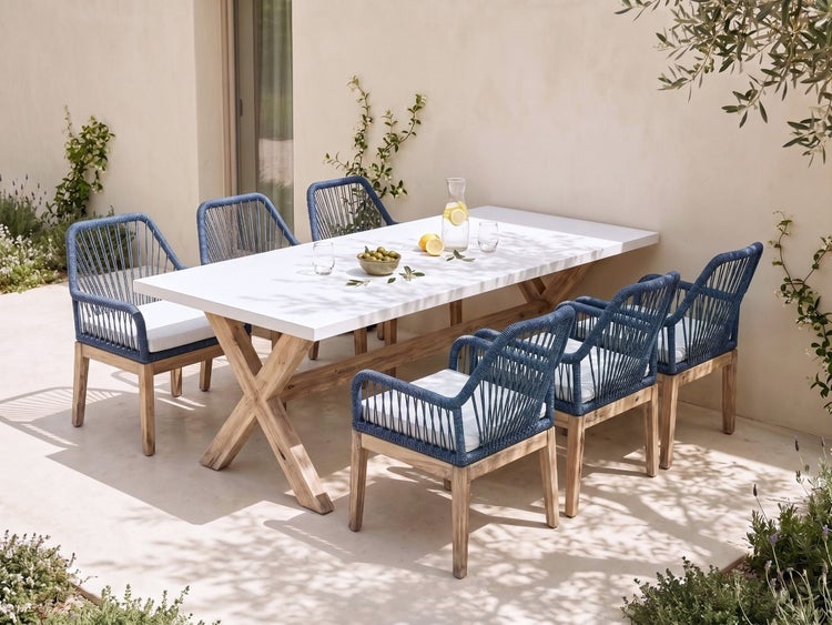 Modernes Gartenmöbel-Set mit einem rechteckigen Holztisch mit weißer Platte und sechs blau bespannten Stühlen auf einer hellen Terrasse.