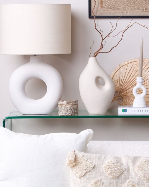 Dekoratives Stillleben mit Lampe, Vase und Kerzenständer auf einem Glastisch