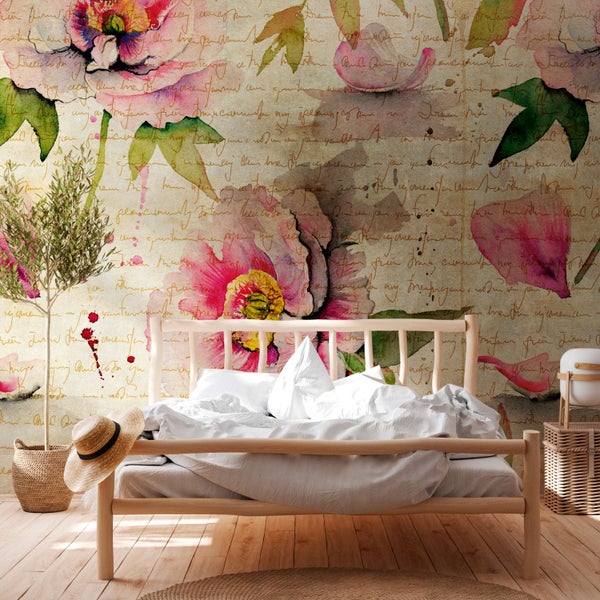Schlafzimmer mit Bett vor einer Fototapete mit Blumen- und Schriftmotiven