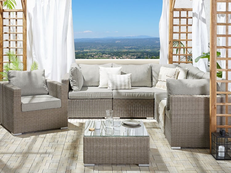 Outdoor-Lounge-Set mit Rattansitzgruppe, Couchtisch und Kissen auf einer Terrasse mit Ausblick