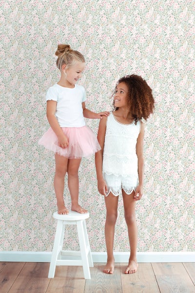 Mädchen stehen vor einer Wand mit Blumentapete