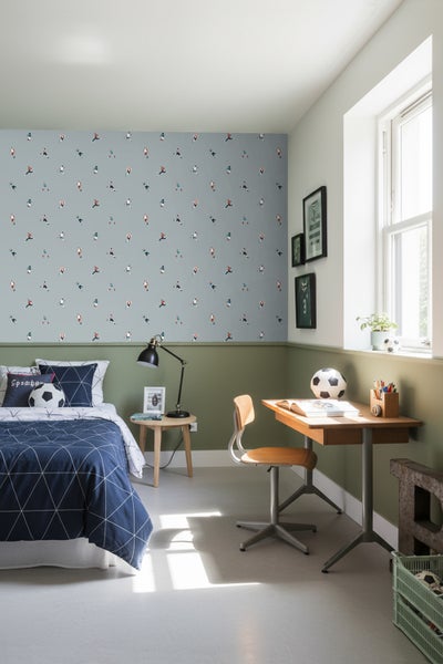 Jugendzimmer mit Bett, Schreibtisch und Fußballmotiven an der Wand.