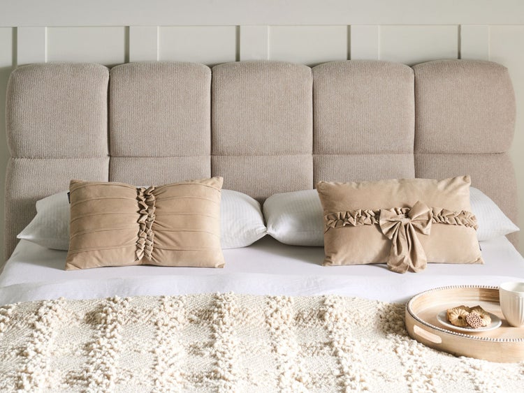 Gemütliches Schlafzimmer mit Stoffkopfteil, Kissen und Tagesdecke