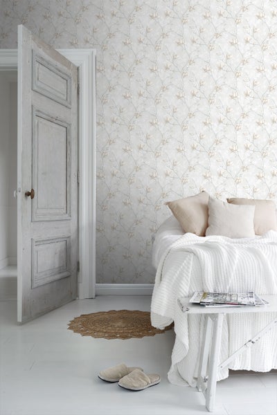 Schlafzimmer mit floraler Tapete, Bett, Nachttisch und geöffneter Tür