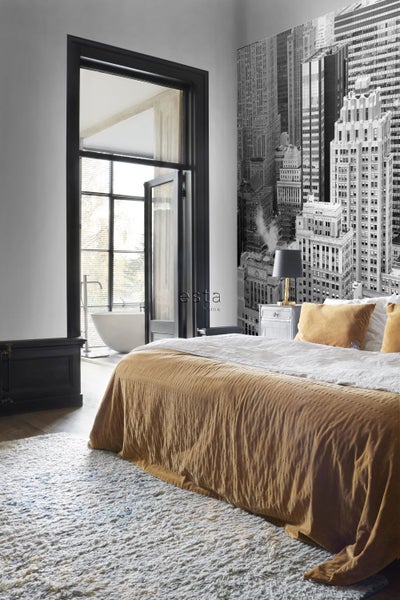 Schlafzimmer mit Bett, Teppich und Fototapete mit Stadtmotiv