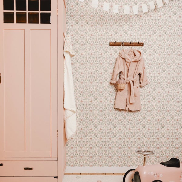 Wand mit floral gemusterter Tapete in einem Zimmer mit einem Schrank und einer Hakenleiste mit Bademantel.