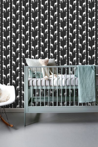 Kinderzimmer mit einer Wandtapete mit Giraffenmuster, einem Kinderbett und einem Schaukelstuhl.