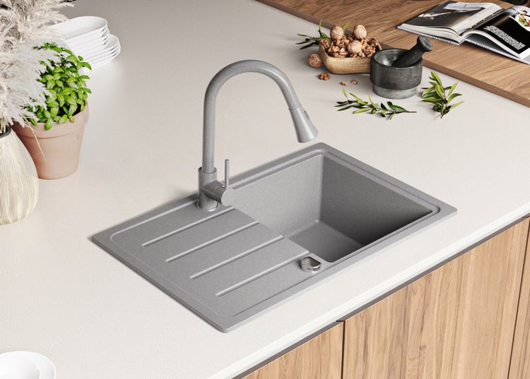 Spüle aus Verbundmaterial mit Abtropffläche und Wasserhahn auf einer Küchentheke.