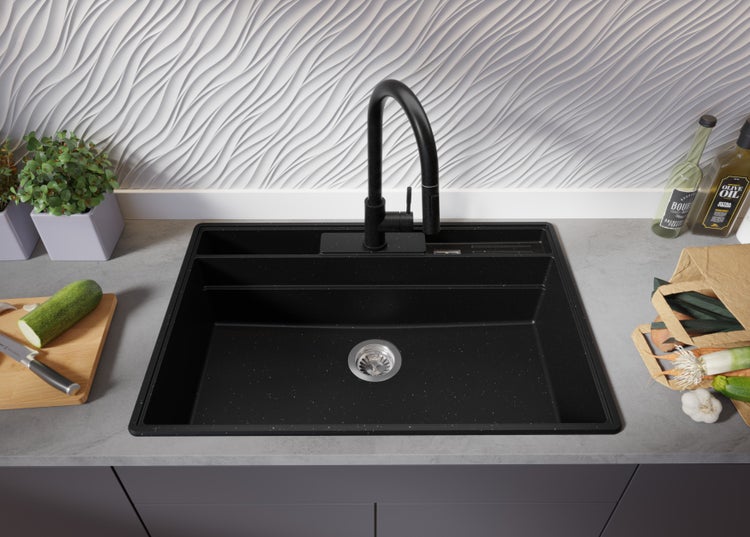 Schwarze Küchenspüle aus Granit mit Armatur auf einer Küchentheke.