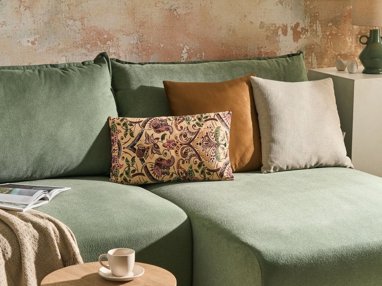 Wohnzimmer mit grüner Couch und dekorativen Kissen