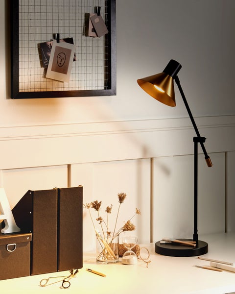 Dekoratives Arrangement mit Schreibtischlampe, Memoboard und Büroartikeln auf einem Schreibtisch