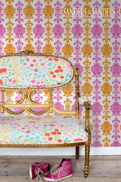Szene mit einer Sitzbank mit Blumenmuster vor einer gemusterten Tapete und Schuhen