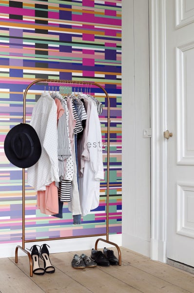Kleiderständer mit verschiedenen Kleidungsstücken und Schuhen vor einer gemusterten Tapete