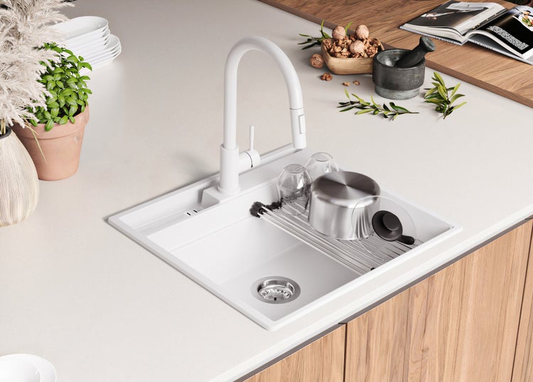 Spüle mit Abtropfgestell, Spültischarmatur und Geschirr auf einer Küchentheke.