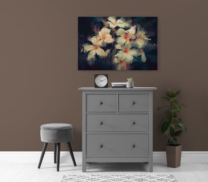 Eine Kommode mit vier Schubladen steht vor einer Wand mit einem Blumenbild, einem Hocker, einer Uhr, Büchern und einer Zimmerpflanze.