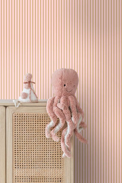 Vliestapete mit feinem vertikalem Streifenmuster in einem Kinderzimmer mit einer Kommode aus Rattan und einem Stofftier in Tintenfischform