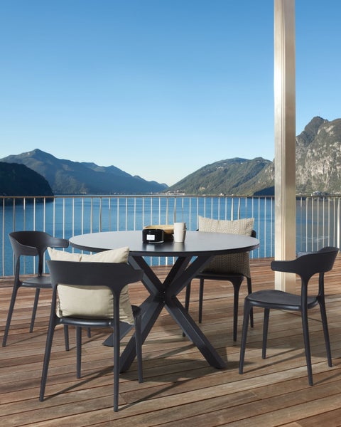 Gartensitzgruppe mit rundem Tisch und vier Stühlen auf einer Terrasse mit Seeblick