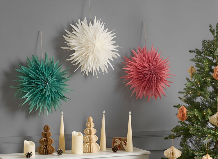 Dekoratives Arrangement mit Papiersternen, Kerzen und Weihnachtsbaum