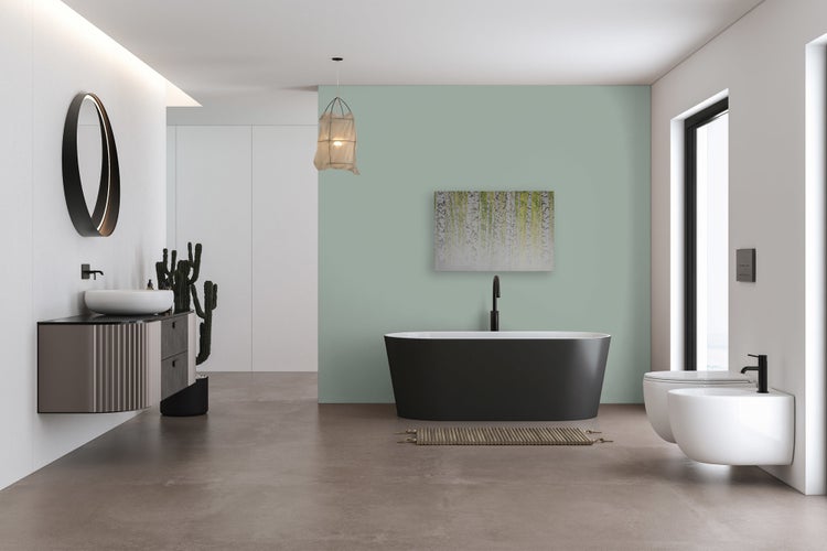 Modernes, geräumiges Badezimmer mit freistehender Badewanne, wandhängendem Waschbecken, Toilette und Bidet vor einer grünen Akzentwand.