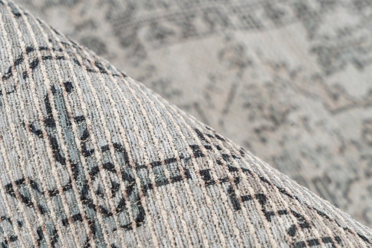 Detailaufnahme eines strukturierten Teppichs mit grauem Vintage-Muster und gerippter Oberfläche.