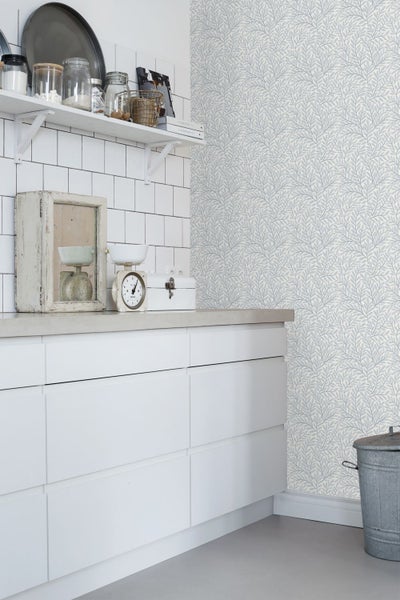Küchenszene mit weißen Schränken und Tapete mit Blattmuster