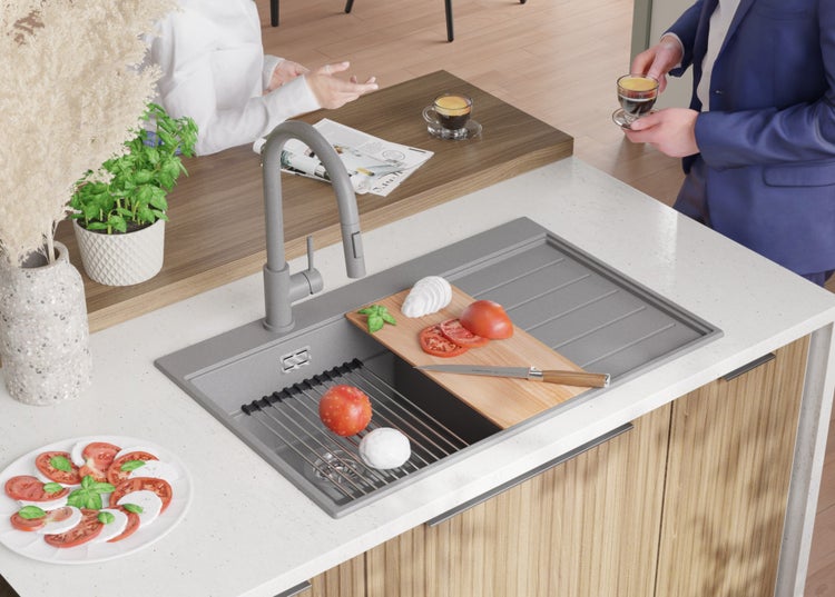 Küchenszene mit Spüle, Armatur, Schneidebrett mit Tomaten und Mozzarella sowie Personen im Hintergrund