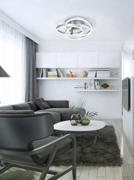 Wohnzimmer mit Sofa, Sessel, Couchtisch, Teppich und Regalen