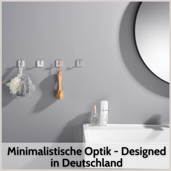 Vier quadratische Metall-Wandhaken in einem minimalistischen Badezimmer mit Duschschwamm, Holzbürste, Waschbecken und Spiegel.
