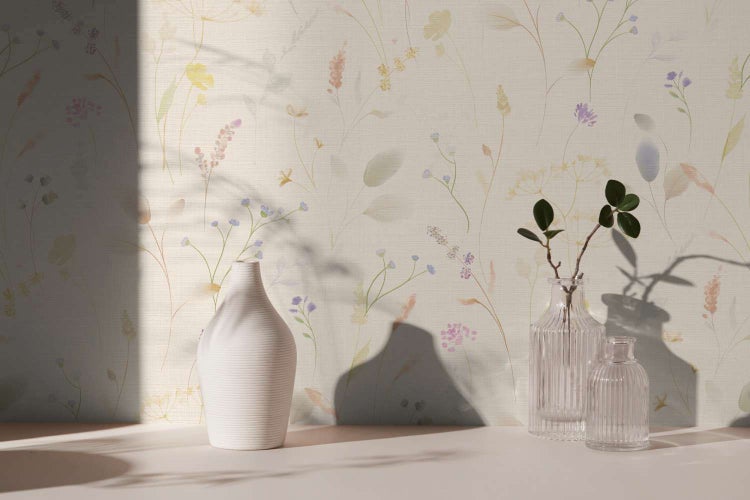 Vliestapete mit zartem Wiesenblumenmuster und filigranen Pflanzenmotiven in einem hellen, wohnlichen Raumambiente.