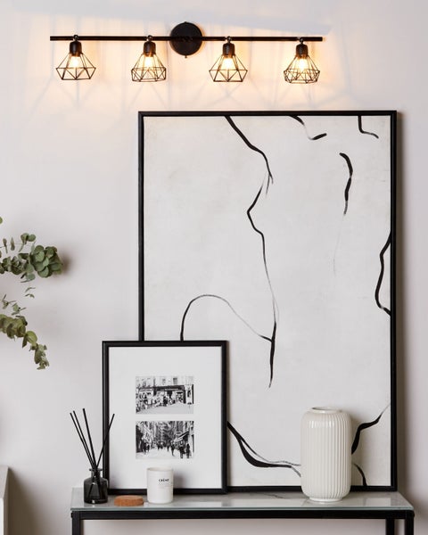 Wandleuchte mit vier Leuchten, abstrakte Kunstwerke und dekorative Accessoires auf einem Tisch