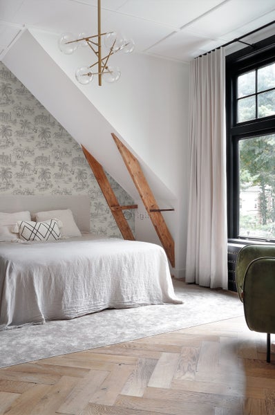 Schlafzimmer im Dachgeschoss mit Bett, gemusterter Tapete und Pendelleuchte