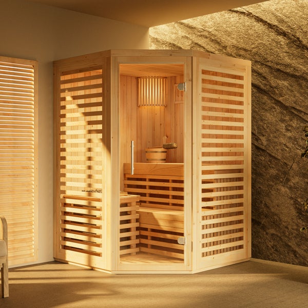 Indoor-Ecksauna aus hellem Holz mit Glastür, zwei Liegeebenen, Saunaofen, Holzeimer und Innenbeleuchtung vor einer Steinwand.