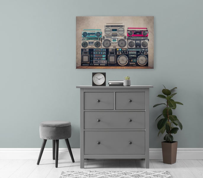 Wandbild mit Motiv von Retro Radiorekordern über einer grauen Kommode mit Hocker und Pflanze in einem modern eingerichteten Raum.