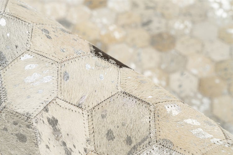 Patchwork-Teppich aus Kuhfell mit Sechseck-Muster, silbernen Metallic-Akzenten und sichtbaren Nähten.