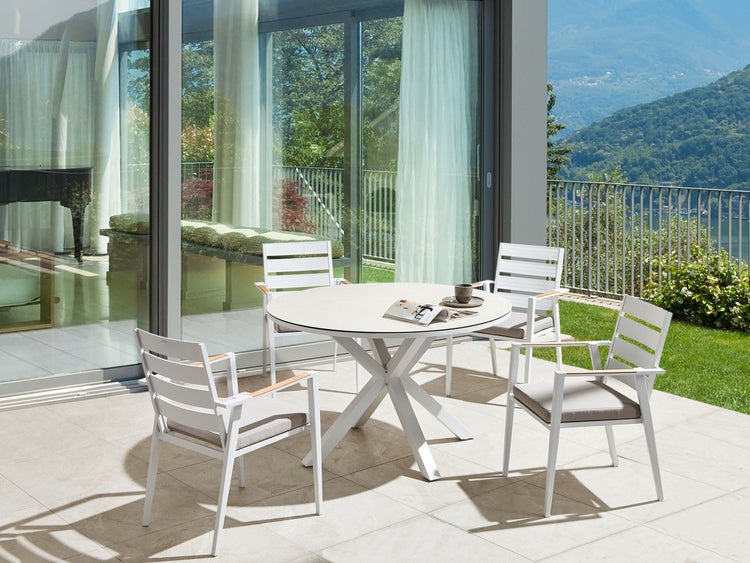 Gartenszene mit rundem Tisch und vier Stühlen auf einer Terrasse mit Ausblick