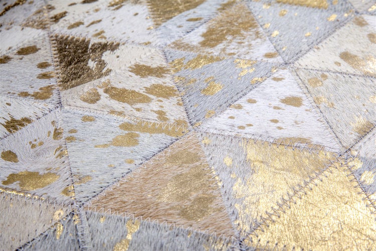 Kuhfell-Teppich in Patchwork-Optik aus dreieckigen Stücken mit goldenen Akzenten und sichtbaren Zickzack-Nähten.